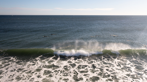 Aerial view of surfers waiting for waves at Sea Bright Beach with breaking surf and white foam in the Atlantic Ocean in Sea Bright New Jersey United States. Aerial view of surfers waiting for waves at Sea Bright Beach with breaking surf and white foam in the Atlantic Ocean in Sea Bright New Jersey United States.