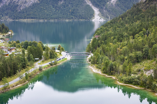 Aerial view of the bridge spanning the serene turquoise waters nestled between verdant forests under the crisp mountain air Plansee Tyrol Austria. Aerial view of the bridge spanning the serene turquoise waters nestled between verdant forests under the crisp mountain air Plansee Tyrol Austria.