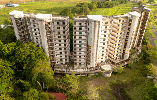 Aerial view of the abandoned Sonesta One Resort buildings surrounded by dense tropical forest and green fields in Jaco Provincia de Puntarenas Costa Rica. Aerial view of the abandoned Sonesta One Resort buildings surrounded by dense tropical forest and green fields in Jaco Provincia de Puntarenas Costa Rica.