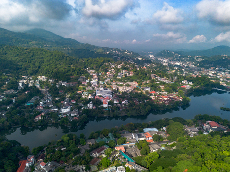 Aerial view of Kandy Lake surrounded by lush green hills dense urban buildings and tropical vegetation in Kandy Central Province Sri Lanka. Aerial view of Kandy Lake surrounded by lush green hills dense urban buildings and tropical vegetation in Kandy Central Province Sri Lanka.
