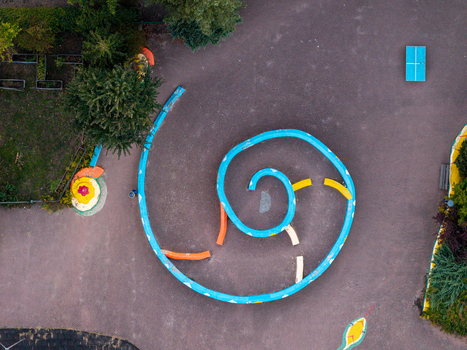 Aerial view of the spiral shaped blue wall structure at High Deck Siedlung surrounded by paved ground trees and colorful playground elements in Berlin Berlin Germany. Aerial view of the spiral shaped blue wall structure at High Deck Siedlung surrounded by paved ground trees and colorful playground elements in Berlin Berlin Germany.
