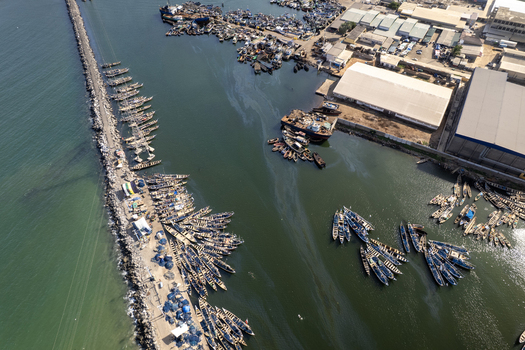 Aerial view of a vibrant harbor where fishing boats cluster densely creating a mosaic of color against the dark water Tema Ghana. Aerial view of a vibrant harbor where fishing boats cluster densely creating a mosaic of color against the dark water Tema Ghana.