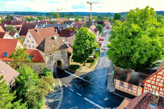 Aerial view of the historic town center featuring red tiled roofs the Erlanger Tor stone gate and lush green trees in Neunkirchen am Brand Bavaria Germany. Aerial view of the historic town center featuring red tiled roofs the Erlanger Tor stone gate and lush green trees in Neunkirchen am Brand Bavaria Germany.