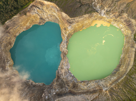 Aerial view of the vibrant turquoise and green crater lakes of Kelimutu National Park surrounded by rugged volcanic rock formations in Detusoko East Nusa Tenggara Indonesia.