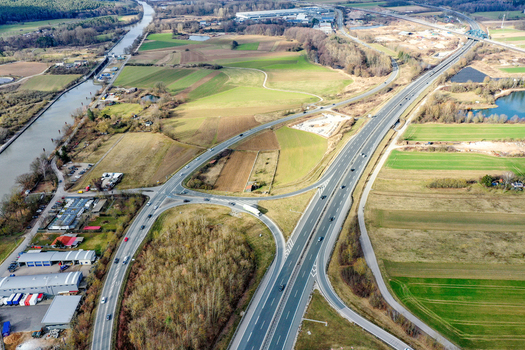 Aerial view of a highway interchange and a canal running through rural landscape with fields and industrial buildings in Buttenheim Bavaria Germany. Aerial view of a highway interchange and a canal running through rural landscape with fields and industrial buildings in Buttenheim Bavaria Germany.