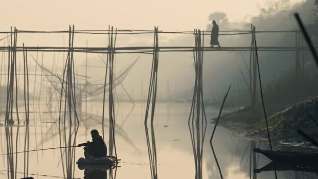 View of a person walking on a bamboo bridge in Bogura Bangladesh. View of a person walking on a bamboo bridge in Bogura Bangladesh.