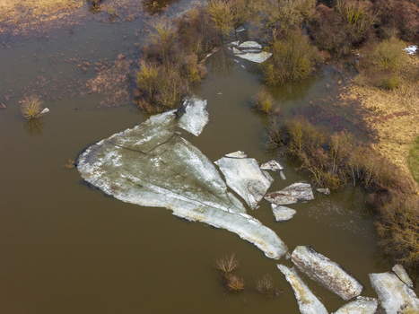Aerial view of large ice floes drifting in flooded river waters surrounded by bare trees and dry meadows Kedainiai Kaunas County Lithuania. Aerial view of large ice floes drifting in flooded river waters surrounded by bare trees and dry meadows Kedainiai Kaunas County Lithuania.