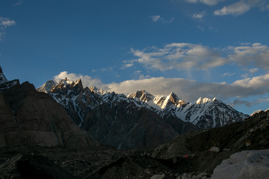 View of the Goro II campsite surrounded by snow capped peaks and rocky mountain terrain under a clear blue sky in Gilgit Pakistan. View of the Goro II campsite surrounded by snow capped peaks and rocky mountain terrain under a clear blue sky in Gilgit Pakistan.