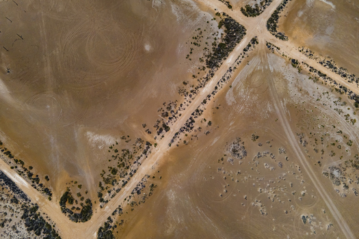 Aerial view of the arid landscape of the Ebro Delta featuring intersecting dirt roads sparse desert vegetation and tire tracks on the sandy ground in Catalonia Spain. Aerial view of the arid landscape of the Ebro Delta featuring intersecting dirt roads sparse desert vegetation and tire tracks on the sandy ground in Catalonia Spain.