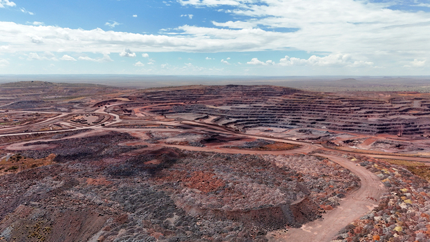 Aerial view of a vast scarred open pit mine with deep red earth and dark terraced pits contrasting with the bright sky Rustenburg North West South Africa. Aerial view of a vast scarred open pit mine with deep red earth and dark terraced pits contrasting with the bright sky Rustenburg North West South Africa.