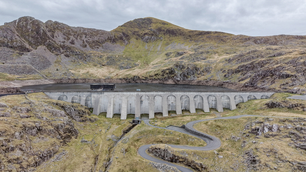 Aerial view of the concrete dam wall contrasting against the rugged mountainous backdrop and winding road below Blaenau Ffestiniog Wales United Kingdom. Aerial view of the concrete dam wall contrasting against the rugged mountainous backdrop and winding road below Blaenau Ffestiniog Wales United Kingdom.