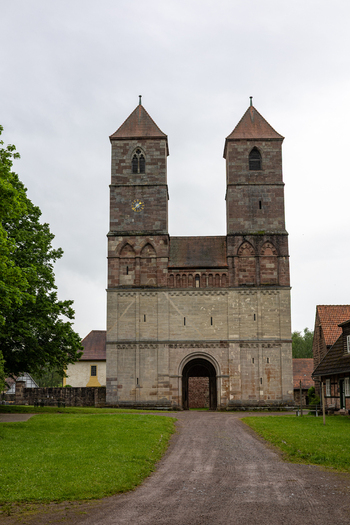 View of Hennebergisches Museum Kloster Vessra with its twin stone towers and arched gateway along a dirt path under a cloudy sky Kloster Vessra Thuringen Germany.