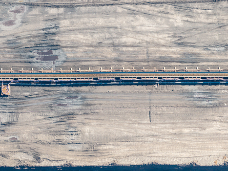 Aerial view of Tagebau Welzow Sud brown coal open pit mine with a long conveyor belt system traversing the vast textured and excavated earth landscape in Spremberg Brandenburg Germany. Aerial view of Tagebau Welzow Sud brown coal open pit mine with a long conveyor belt system traversing the vast textured and excavated earth landscape in Spremberg Brandenburg Germany.