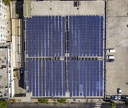 Los Angeles United States 16 August 2018 Aerial view of a large solar array installed on a flat building rooftop with surrounding urban infrastructure. Los Angeles United States 16 August 2018 Aerial view of a large solar array installed on a flat building rooftop with surrounding urban infrastructure.