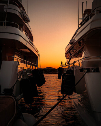 Balearic Islands Spain 15 September 2023 View of two luxury yachts moored in a marina during a vibrant golden sunset with calm water reflecting the orange sky. Balearic Islands Spain 15 September 2023 View of two luxury yachts moored in a marina during a vibrant golden sunset with calm water reflecting the orange sky.