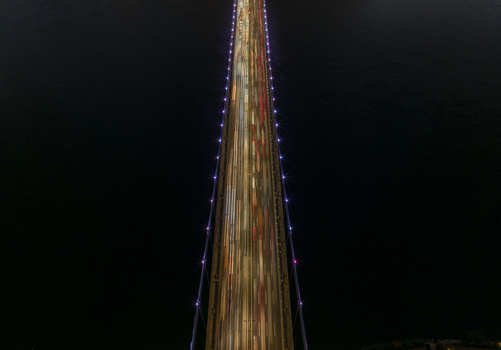 Aerial view of Fatih Sultan Mehmet Bridge at night with long exposure light trails from traffic illuminated suspension cables and dark waters in Beykoz Istanbul Turkey. Aerial view of Fatih Sultan Mehmet Bridge at night with long exposure light trails from traffic illuminated suspension cables and dark waters in Beykoz Istanbul Turkey.