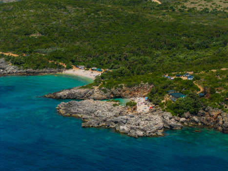 Aerial view of Aquarium Beach featuring turquoise water rocky cliffs and lush green vegetation in Jala Vlore County Albania. Aerial view of Aquarium Beach featuring turquoise water rocky cliffs and lush green vegetation in Jala Vlore County Albania.