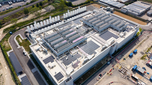 Aerial view of a modern data center campus featuring rooftop solar panels cooling units and industrial infrastructure in Melegnano Lombardy Italy.