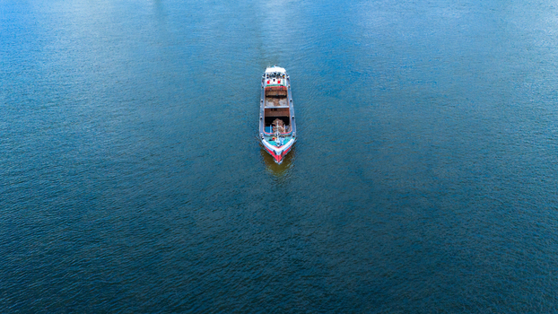 Aerial view of a cargo barge navigating the blue waters of the Danube river with gentle ripples Novi Sad Vojvodina Serbia. Aerial view of a cargo barge navigating the blue waters of the Danube river with gentle ripples Novi Sad Vojvodina Serbia.