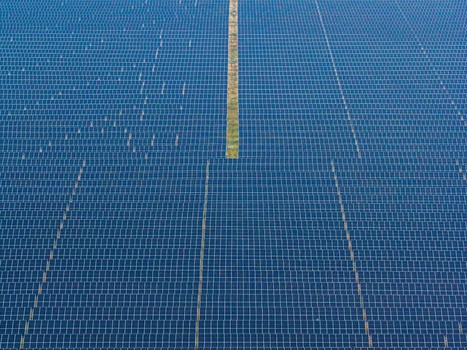 Aerial view of a vast solar farm with rows of blue photovoltaic panels arranged in a grid pattern across the landscape in Poland.