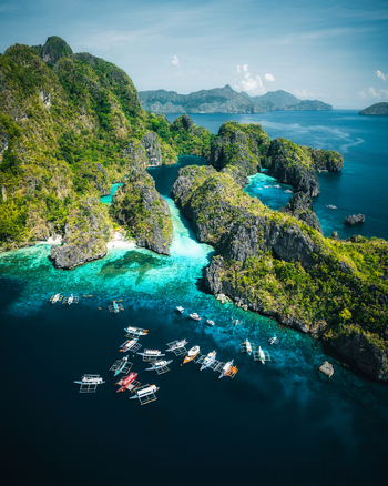 Aerial view of Big Lagoon with turquoise waters limestone cliffs and traditional outrigger boats in El Nido Bay Philippines. Aerial view of Big Lagoon with turquoise waters limestone cliffs and traditional outrigger boats in El Nido Bay Philippines.