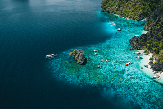Aerial view of turquoise waters coral reefs limestone cliffs and traditional outrigger boats in El Nido Mimaropa Philippines. Aerial view of turquoise waters coral reefs limestone cliffs and traditional outrigger boats in El Nido Mimaropa Philippines.