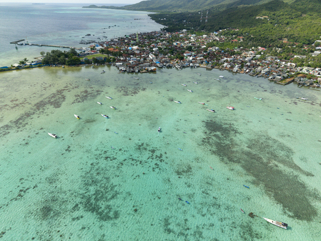 Aerial view of boats scattered on shallow turquoise waters near a densely populated shoreline Karimunjawa Central Java Indonesia. Aerial view of boats scattered on shallow turquoise waters near a densely populated shoreline Karimunjawa Central Java Indonesia.