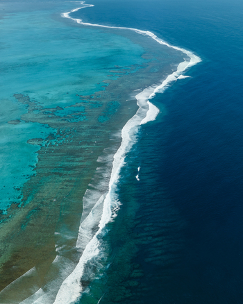 Aerial view of the dramatic contrast between the turquoise lagoon and the deep blue ocean separated by a line of white waves Noumea South Province New Caledonia.