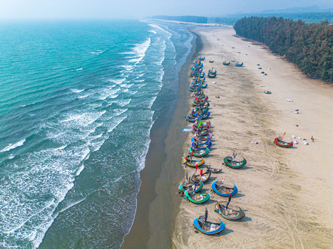 Aerial view of vibrant fishing boats resting on the sandy shore where the turquoise sea meets the land Cox s Bazar Chittagong Division Bangladesh.