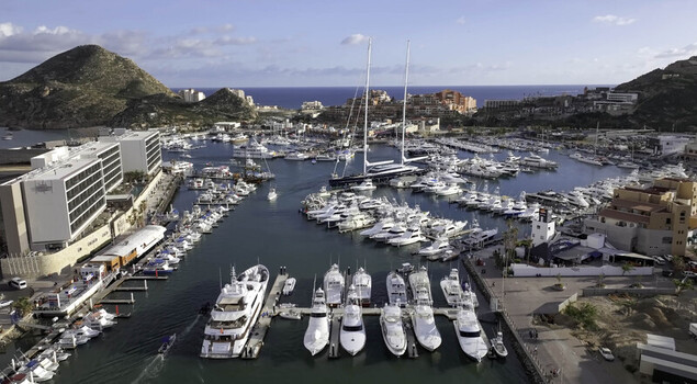 Aerial view of Cabo San Lucas Marina filled with luxury yachts and boats surrounded by modern waterfront buildings and hills in Cabo San Lucas Baja California Sur Mexico.