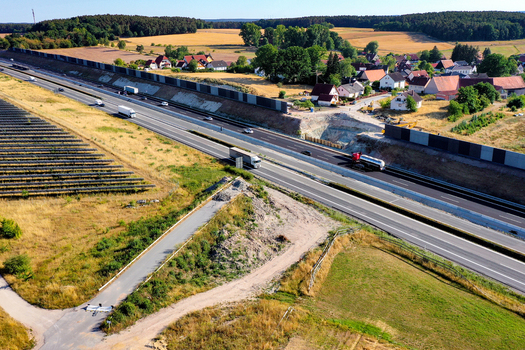 Aerial view of a busy highway with trucks passing by noise barriers and a solar farm near a rural village Hochstadt Bavaria Germany. Aerial view of a busy highway with trucks passing by noise barriers and a solar farm near a rural village Hochstadt Bavaria Germany.