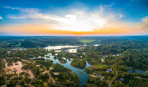 Aerial view of a serene lake system surrounded by lush forests and residential houses under a vibrant sunset sky in Jelgava Latvia. Aerial view of a serene lake system surrounded by lush forests and residential houses under a vibrant sunset sky in Jelgava Latvia.