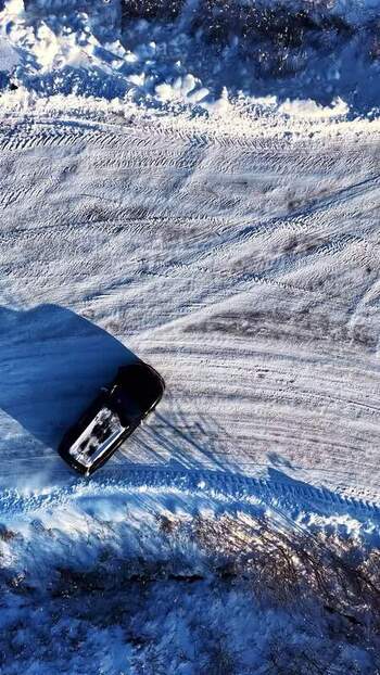 Aerial view of a car on a snowy road in Latvia.