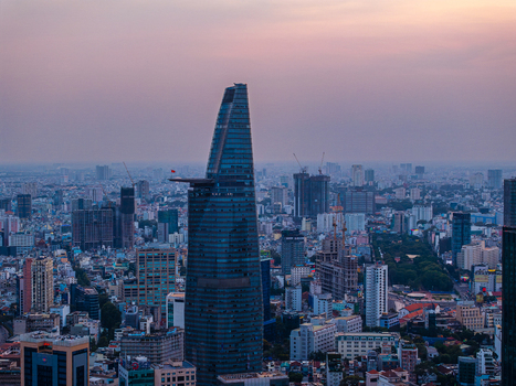 Aerial view of Bitexco Financial Tower rising above the dense urban skyline at sunset with glass facades reflecting the soft light and surrounding high rise buildings Ho Chi Minh City Vietnam. Aerial view of Bitexco Financial Tower rising above the dense urban skyline at sunset with glass facades reflecting the soft light and surrounding high rise buildings Ho Chi Minh City Vietnam.
