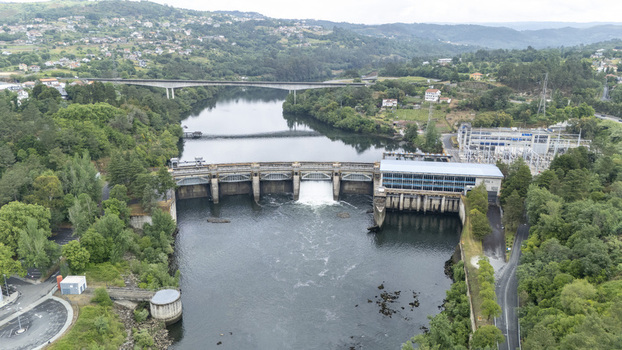 Aerial view of the Velle Hydroelectric Power Station and dam on the Mino River with lush green hills and a bridge in the background Ourense Ourense Spain.