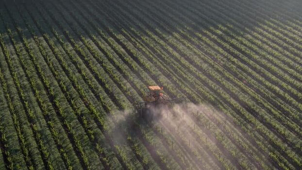 Aerial view of a tractor spraying a vineyard in France. Aerial view of a tractor spraying a vineyard in France.