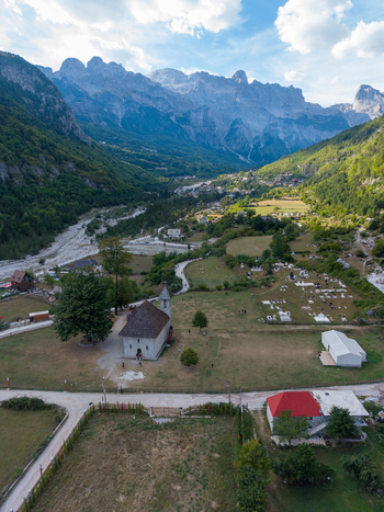 Aerial view of the historic stone church and cemetery nestled in the green valley of the Accursed Mountains in Theth Shkoder County Albania. Aerial view of the historic stone church and cemetery nestled in the green valley of the Accursed Mountains in Theth Shkoder County Albania.