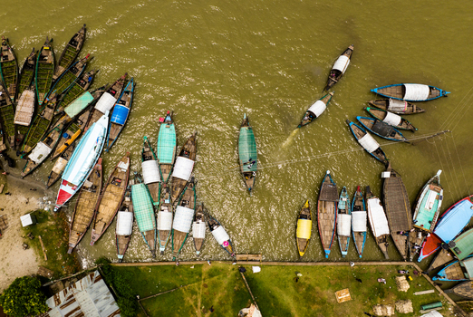 Aerial view of Baish Mowza Sarak Bazar with numerous traditional wooden boats moored along the riverbank in Nabinagar Chittagong Division Bangladesh. Aerial view of Baish Mowza Sarak Bazar with numerous traditional wooden boats moored along the riverbank in Nabinagar Chittagong Division Bangladesh.