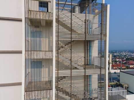 Aerial view of a modern building facade featuring a metal louvered staircase enclosure with visible stairs and doors in Purwokerto Central Java Indonesia. Aerial view of a modern building facade featuring a metal louvered staircase enclosure with visible stairs and doors in Purwokerto Central Java Indonesia.