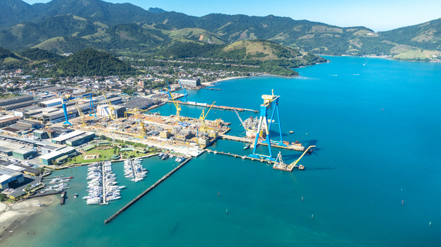 Aerial view of the shipyard facility with a large gantry crane industrial structures and a marina filled with yachts along the turquoise coastline in Angra dos Reis Rio de Janeiro Brazil.