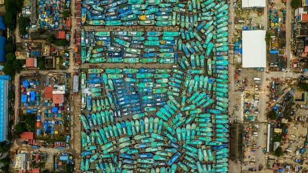 Aerial view of Malpe Fishing Harbour with numerous colorful fishing boats docked in rows surrounded by urban infrastructure in Udupi Karnataka India. Aerial view of Malpe Fishing Harbour with numerous colorful fishing boats docked in rows surrounded by urban infrastructure in Udupi Karnataka India.
