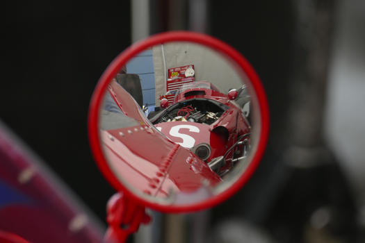 Chichester United Kingdom 21 July 2018 View of a vibrant red vintage race car reflected in a circular mirror capturing the essence of Goodwood s racing heritage.. Chichester United Kingdom 21 July 2018 View of a vibrant red vintage race car reflected in a circular mirror capturing the essence of Goodwood s racing heritage..