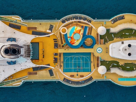 Aerial view of a cruise ship deck featuring a blue water slide a basketball court and swimming pools surrounded by the sea in Cannes Provence Alpes Cote d Azur France. Aerial view of a cruise ship deck featuring a blue water slide a basketball court and swimming pools surrounded by the sea in Cannes Provence Alpes Cote d Azur France.