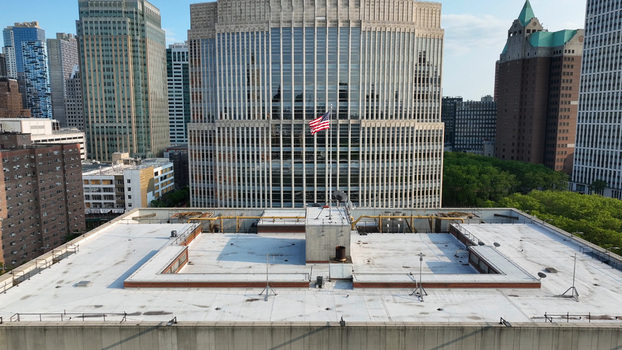 Aerial view of a rooftop with an American flag in the foreground surrounded by tall skyscrapers and urban architecture in New York New York United States.