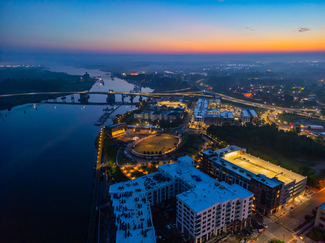 Aerial view of Riverfront Park along the Cape Fear River at dusk with city lights and bridge in Wilmington North Carolina United States.