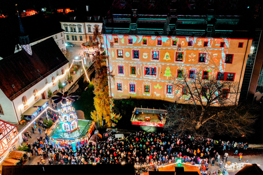 Forchheim Germany 20 December 2025 Aerial view of the Weihnachtsmarkt Forchheim with the advent calendar projection on the Kaiserpfalz facade and crowds of people at night.