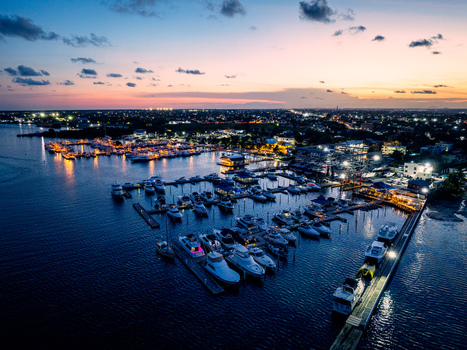 Aerial view of Club Nautico de Santo Domingo Inc. with numerous yachts and boats docked in the marina at twilight featuring city lights reflecting on the calm water in Andres Santo Domingo Dominican Republic. Aerial view of Club Nautico de Santo Domingo Inc. with numerous yachts and boats docked in the marina at twilight featuring city lights reflecting on the calm water in Andres Santo Domingo Dominican Republic.
