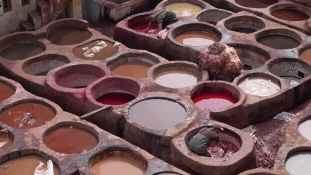 View of workers dyeing leather in the historic Chouara Tannery Morocco.