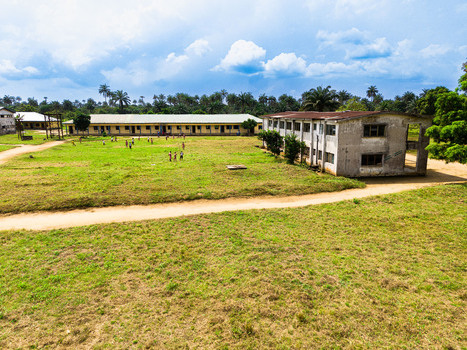 Aerial view of school buildings and a grassy courtyard with children playing under a cloudy sky in Ahoada I Rivers Nigeria. Aerial view of school buildings and a grassy courtyard with children playing under a cloudy sky in Ahoada I Rivers Nigeria.