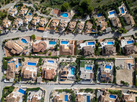 Aerial view of residential villas with private swimming pools terracotta rooftops and winding streets in Moraira Valencian Community Spain.
